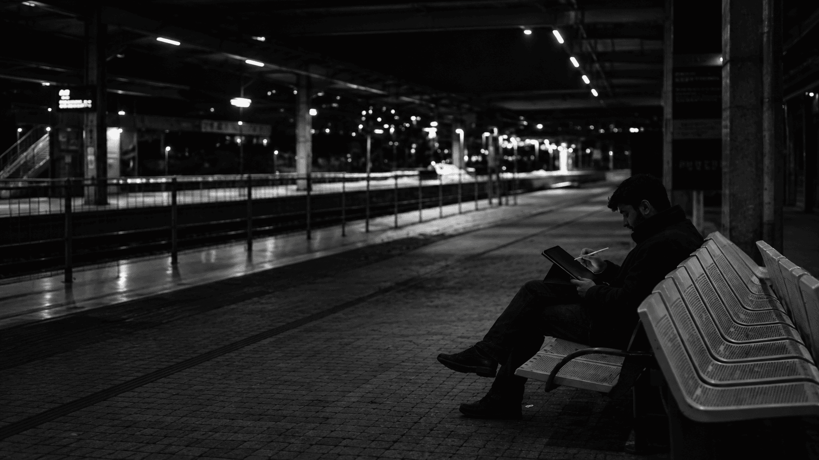 Vedas Dixit sketching on an iPad on a railway platform at night